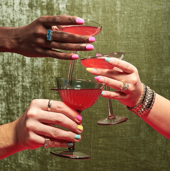 Hands holding cocktail glasses with manicures