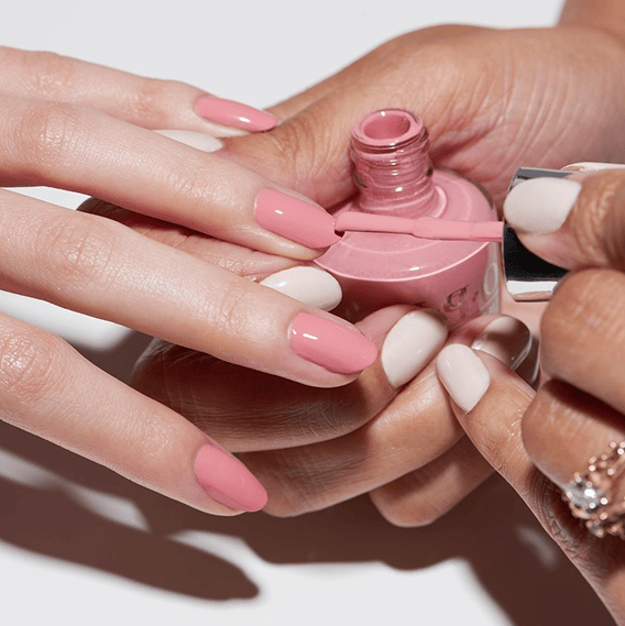 Hands holding a pink nail polish bottle