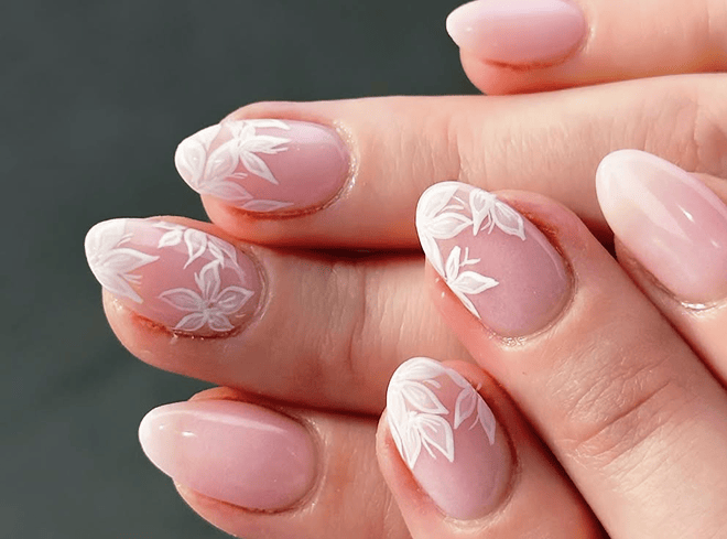 White floral nail art on pink base